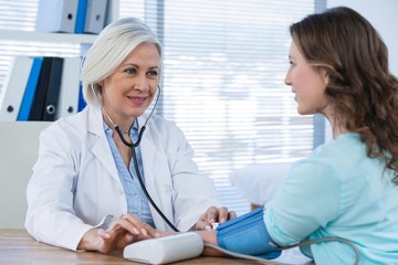 Female doctor checking blood pressure of a patient