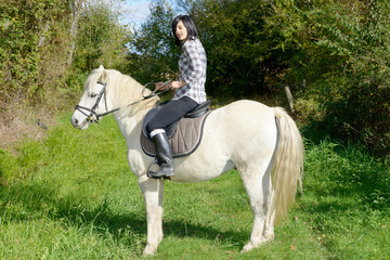 young beautiful brunette woman riding horse