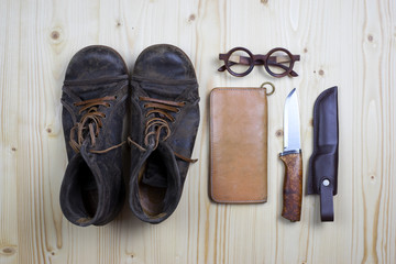 Boots and leather wallet on flat pine wood.