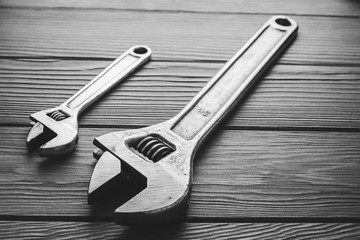 Adjustable wrenches, spanners on wooden texture. Black and white