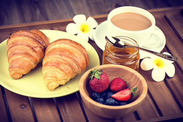 Cup of coffee and croissants on wooden background. Toned image