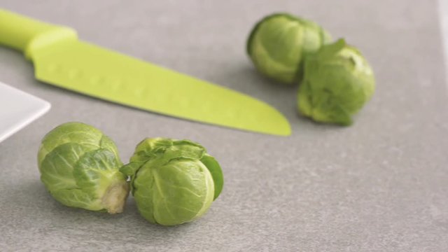 Brussel Sprouts On Kitchen Table With Green Knife. Preparation Of Vegetable For Vegetarian Food.