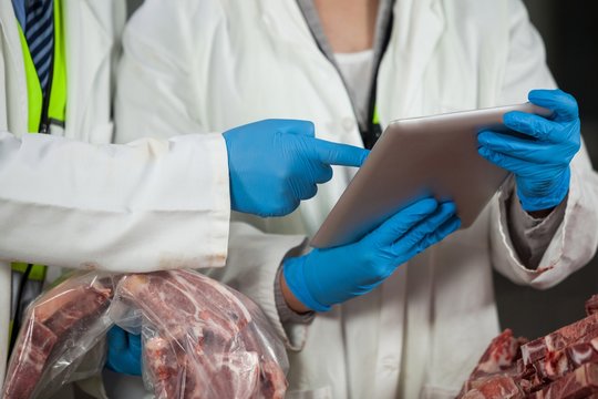 Technician using digital tablet while examining meat - Powered by Adobe