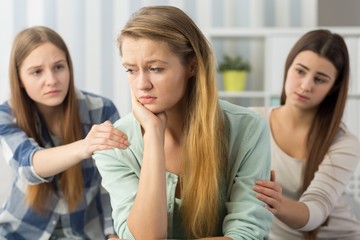 Two friends comforting sorrowful teenager
