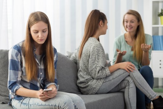Excluded teenager looking at smartphone