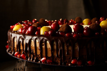 Triple chocolate cake decorated with pomegranate, cranberries and small apples.