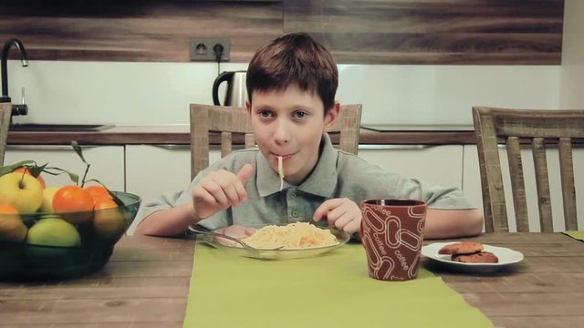 Boy eating pasta in the kitchen