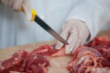 Butcher cutting meat at meat factory