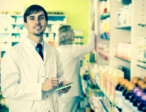 Pharmacist And Pharmacy Technician Posing In Drugstore