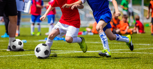 Football Soccer Match for Children. Kids Playing Soccer Game Tournament. Boys Running and Kicking Football. Youth Soccer Coach in the Background - obrazy, fototapety, plakaty