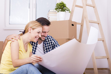 Young smiling couple discussing plan of their new house. Moving and renovation concept