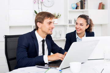 Two office workers work using laptops