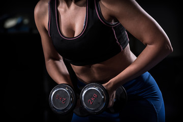 Woman bodybuilder  lifting dumbbell isolated over black background