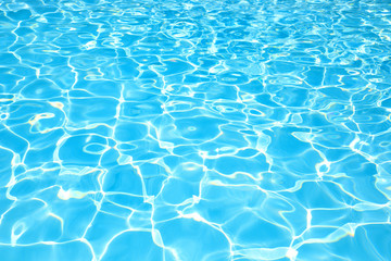Blue water surface in swimming pool with sun reflection