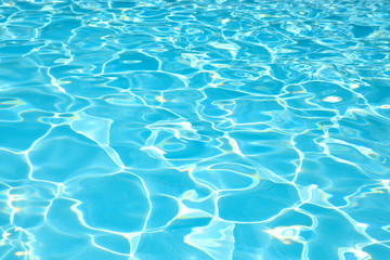 Blue water surface in swimming pool with sun reflection