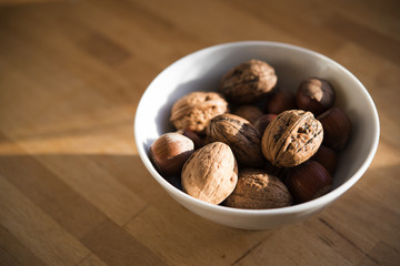 Fresh walnuts in a white bowl on a wooden table, copy space