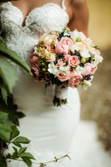 beautiful tender wedding bouquet of roses and eustoma flowers in hands of the bride