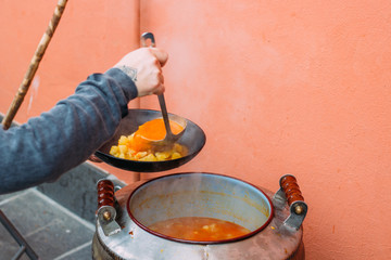 Woman serving hot food from a large pot.