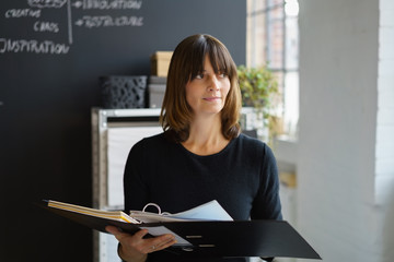 frau steht im büro und schaut nachdenklich zur seite