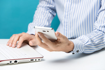 Male hands, Notebook and smart-phones for business in the office on blue background
