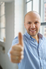 mann steht am fenster und zeigt daumen hoch