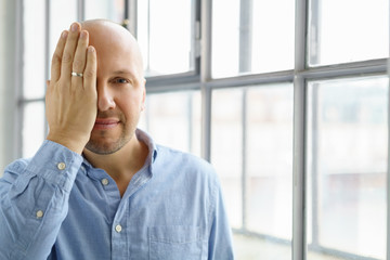mann hält die hand vor ein auge
