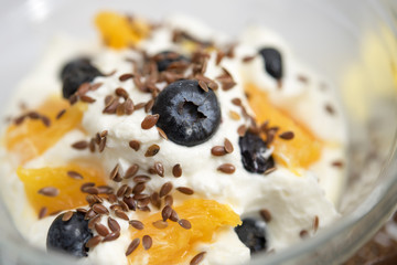 Quark, yogurt or cottage cheese, with fresh blueberries, oranges and flax seeds, closeup