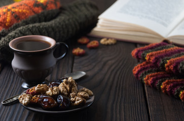 Cup of coffee, book and knit cap on wooden table