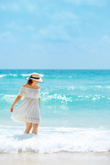 Fototapeta na wymiar Woman in white dress walking on the beach during summer vacation