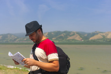 Camper,tourist in nature by the river looking at his map