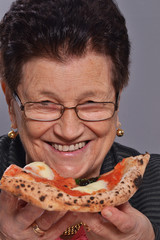 señora anciana comiendo pizza.