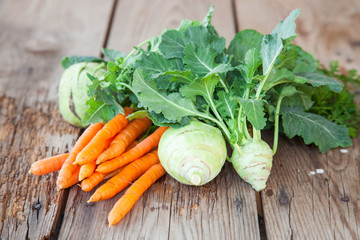 cabbage of a kohlrabi and carrots with a tops of vegetable on a table, selective focus