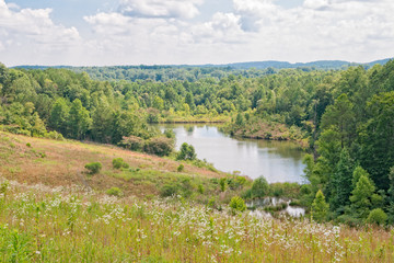 Small lake along Interstate 22 in Alabama USA with reflection of clouds in water and a swamp area...