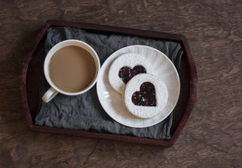 Coffee and cookies-hearts with cranberry jam on a wooden tray. Top view