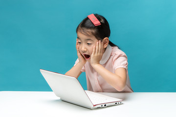 surprised, Cute asia little girl who enjoy the laptop computer on blue background