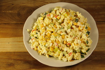 Salad with crab sticks, corn, cucumber, eggs and rice