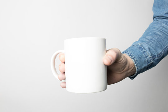 Hand In Blue Shirt Is Holding White Coffee Cup