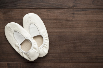 Fototapeta premium child's white dancing shoes on the wooden floor