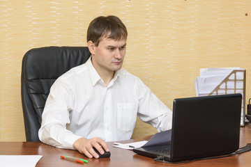 The man at the desk in the office at the computer to view the document