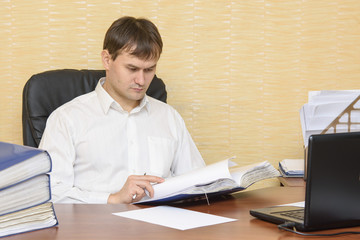 The man at the desk in the office to view documents