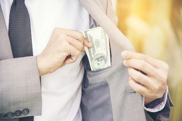 Businessman with dollars bills inside the pocket, concept of corruption.