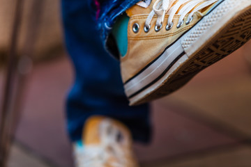 Fototapeta na wymiar Color picture of woman feet wearing yellow sneakers, detail