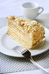 Piece of layer cake with custard and walnuts on a plate