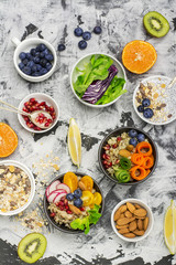 Fototapeta na wymiar Vegetarian Quinoa bowl. Healthy breakfast or snack with detox , tomato, cucumber, carrot, pomegranate seeds, juicy blueberries and lettuce in portioned bowls. Top view