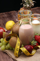 fitness equipment and healthy food - Strawberry Banana smoothie or milkshake(green apple, pepper, grapes, nectarines, kiwi, orange, dumbbells and measuring tape) 