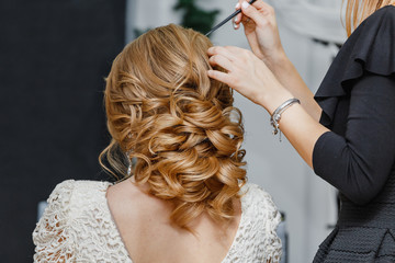 Jeune mariée se faisant coiffer avant le mariage par un coiffeur professionnel