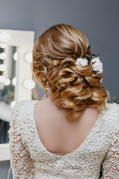 rear view of a bride with curly wedding hairstyle with cotton flowers as winter image