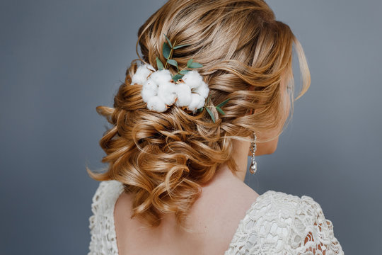 Rear view close-up of the finished wedding hairstyles in the form of winter bride with cotton flowers decoration