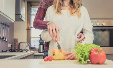 Loving couple cooking together vegetables at home.