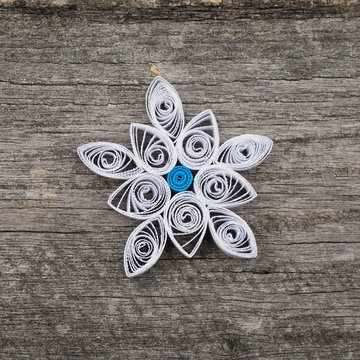Paper snowflake made with quilling technique on a wooden surface
